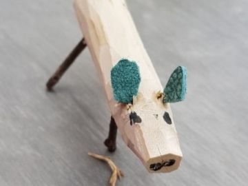 Geschnitztes Holzschwein mit petrolfarbenen Stoffohren auf einem Tisch in der BEB in Norderstedt der OGGS Harksheide Nord