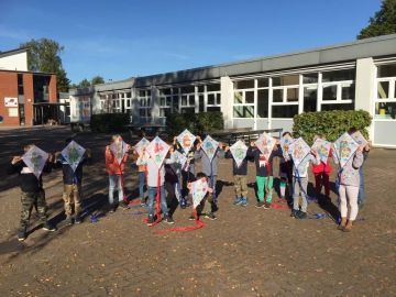 Kinder mit selbst gebastelten Drachen auf dem Schulhof der OGGS Falkenberg in Norderstedt