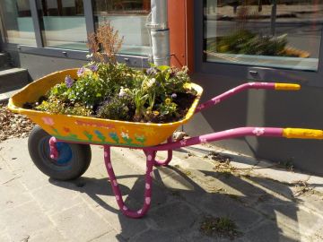 Bemalte Schubkarre mit Pflanzen vor der Mensa der OGGS Glashütte in Norderstedt