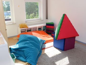 Vielseitig genutzter Raum mit Sitzkissen, Bauwürfeln und Teppich zum Spielen und Entspannen in der Nachmittagsbetreuung der Ganztagsschule in Norderstedt