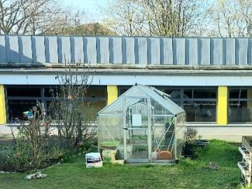 Gewächshaus und Beete im Schulgarten der OGGS Heidberg in Norderstedt
