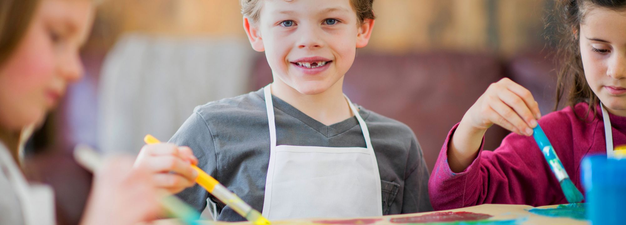 Drei Kinder beim Malen mit dicken und bunten Pinseln einem Raum